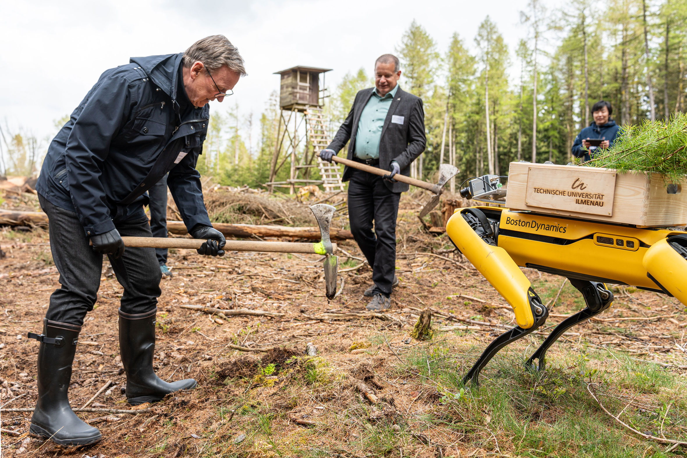 Bodo Ramelow (li.) und Institutsleiter Joachim Bös pflanzen mit Roboterhund Bäume.