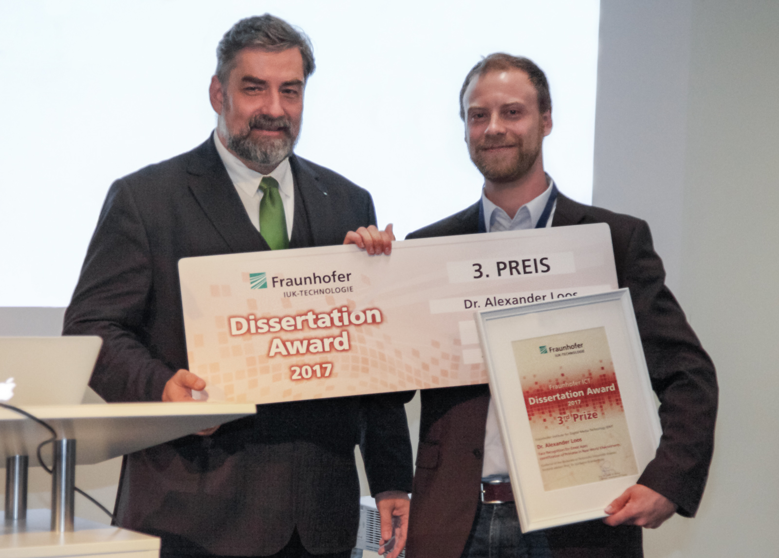 Alexander Nouak, Geschäftsführer des Fraunhofer-Verbunds IUK-Technologie (li.) überreicht den mit 2000 Euro dotierten Preis an Dr. Alexander Loos vom Fraunhofer IDMT. 