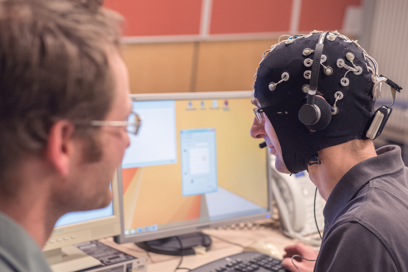 Mann bei EEG Messung vor Bildschirmen